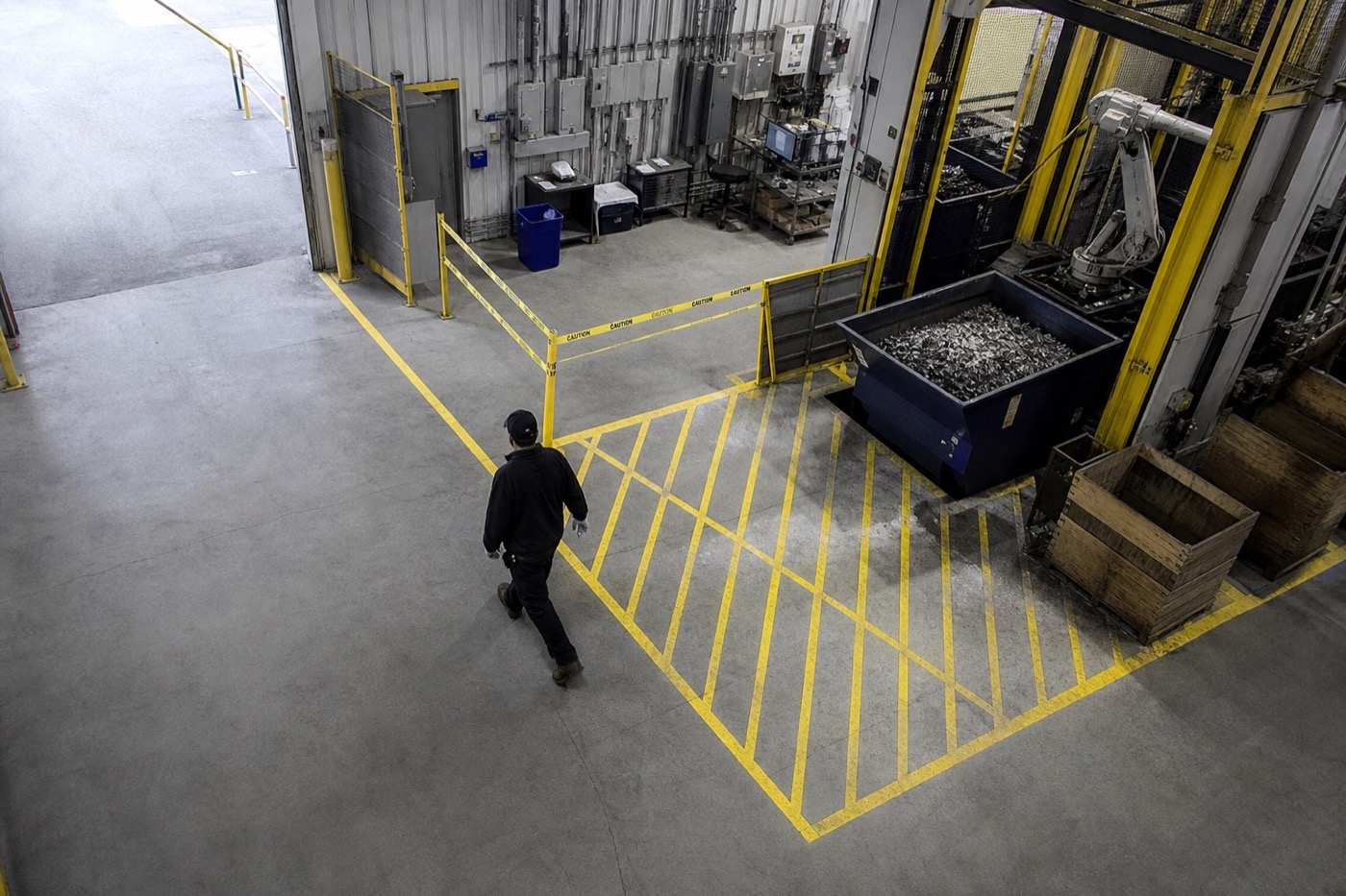 Person crossing yellow restricted-area markings inside a hazardous warehouse zone
